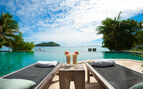 view of two luxury deck chairs facing the blue sea with palm trees 