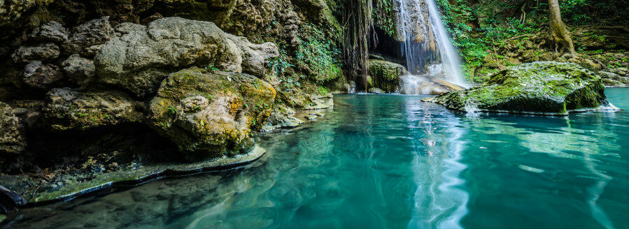 Photo showing the calm water surface with a waterfall in the backgound 