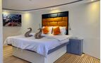 cabin on a boat showing a double bed with towel swans, orange pillows and an orange headboard